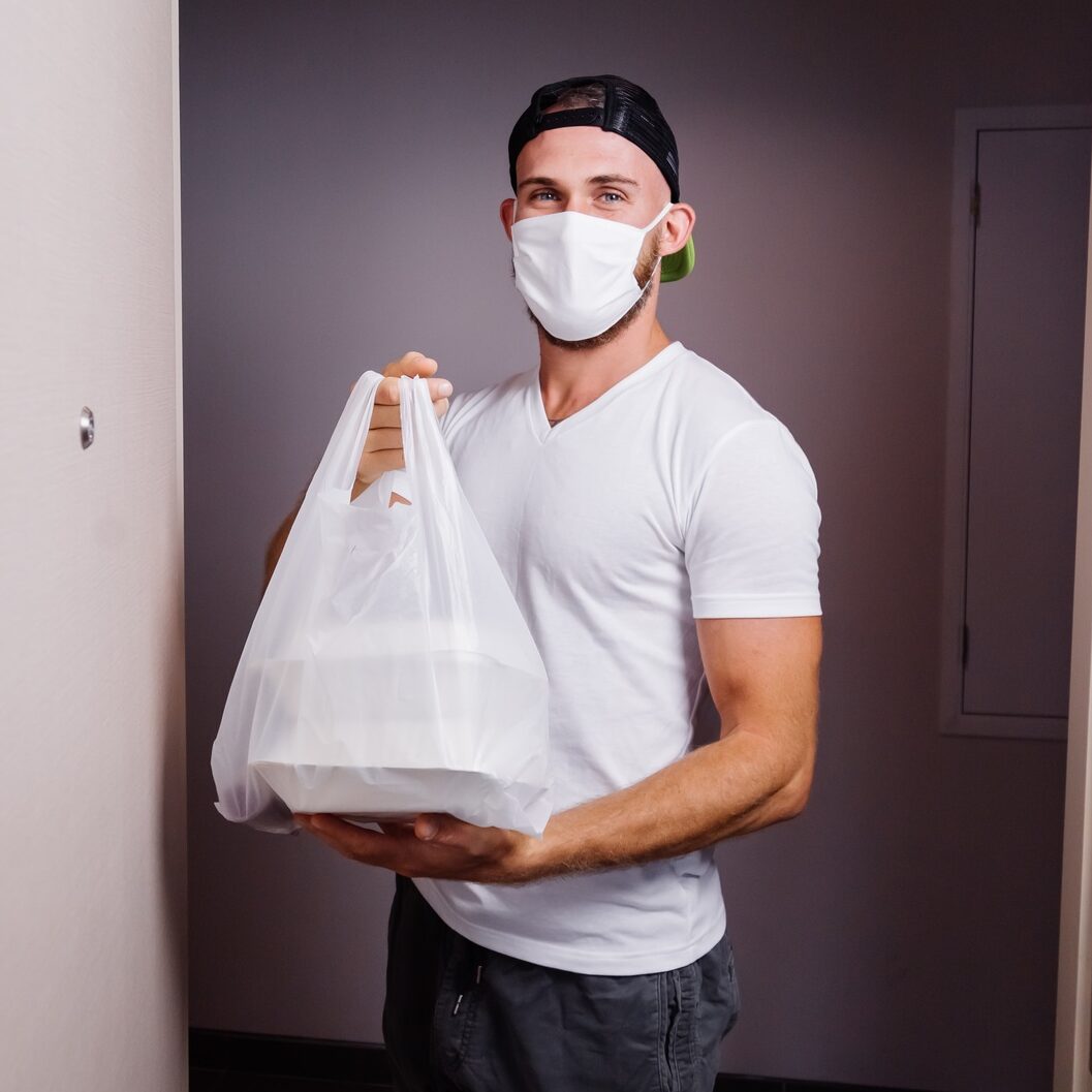 deliver man wearing face medical mask handling plastic bag of food