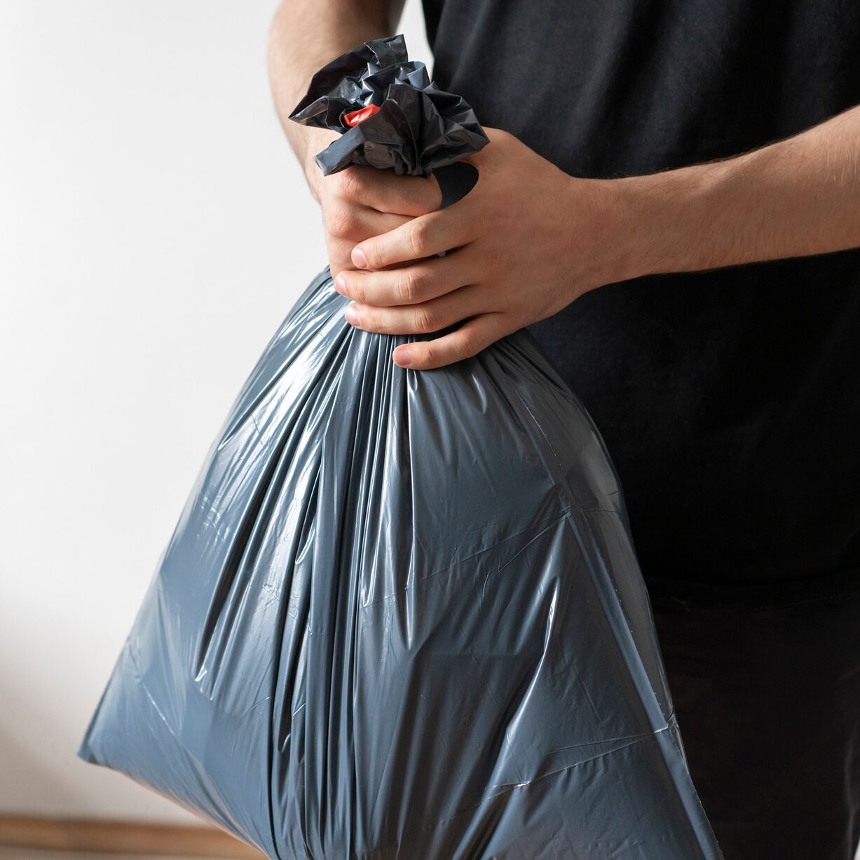 holding plastic garbage bag, take out the trash